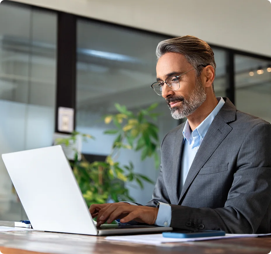 Business executive working on laptop in modern office.