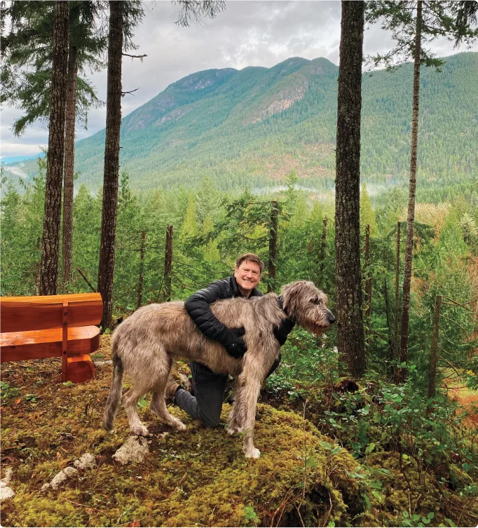 TELUS President and CEO, Darren Entwistle, hiking in the forest with his dog.