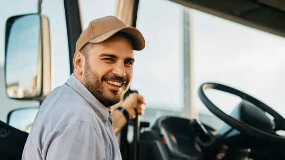 A truck driver smiles as he climbs into his truck.