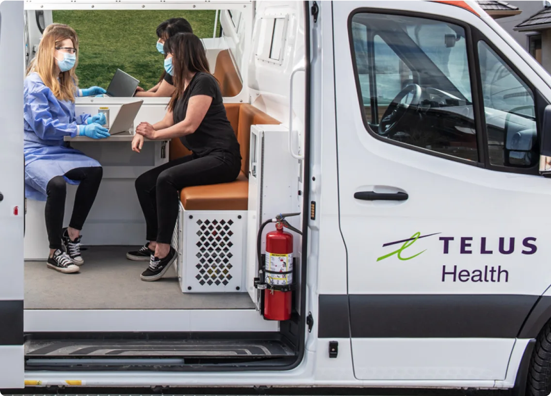 A doctor chatting with a patient in a TELUS Health van. 