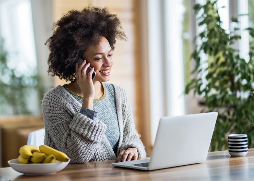 A woman seated at a table, working on a laptop.