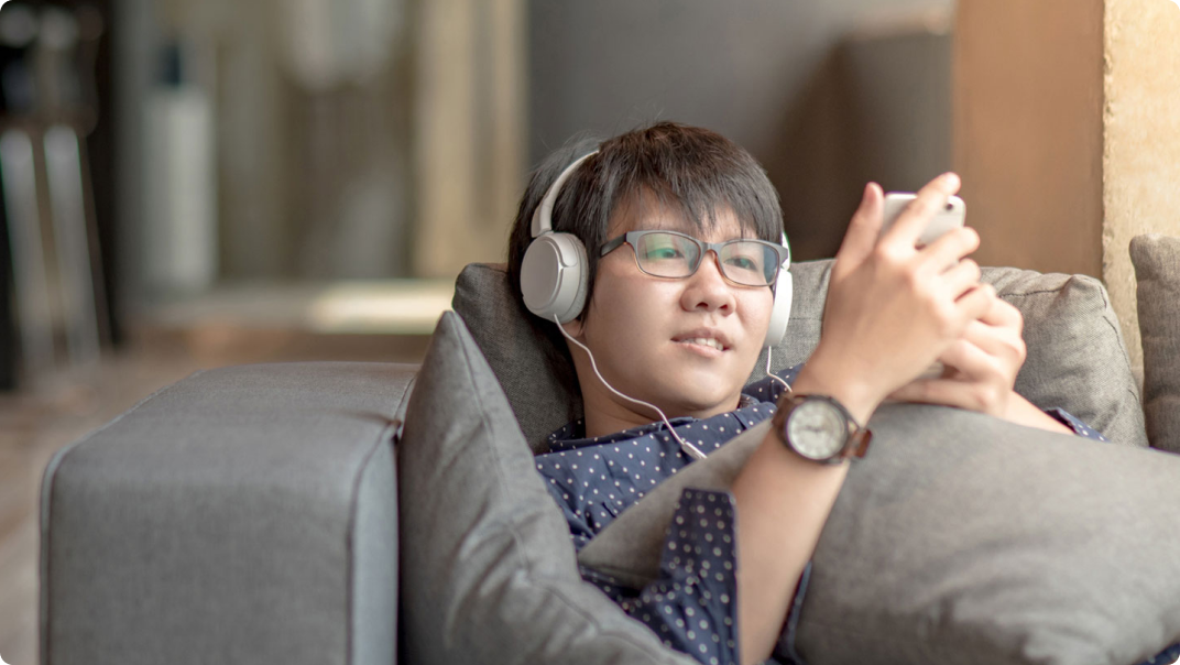 A teenager with headphones on using cognitive accessibility features on his smartphone