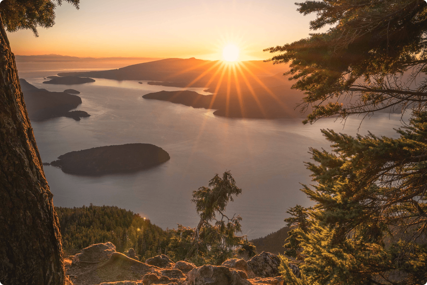 A landscape photo of Howe Sound and surrounding mountains at sunset.