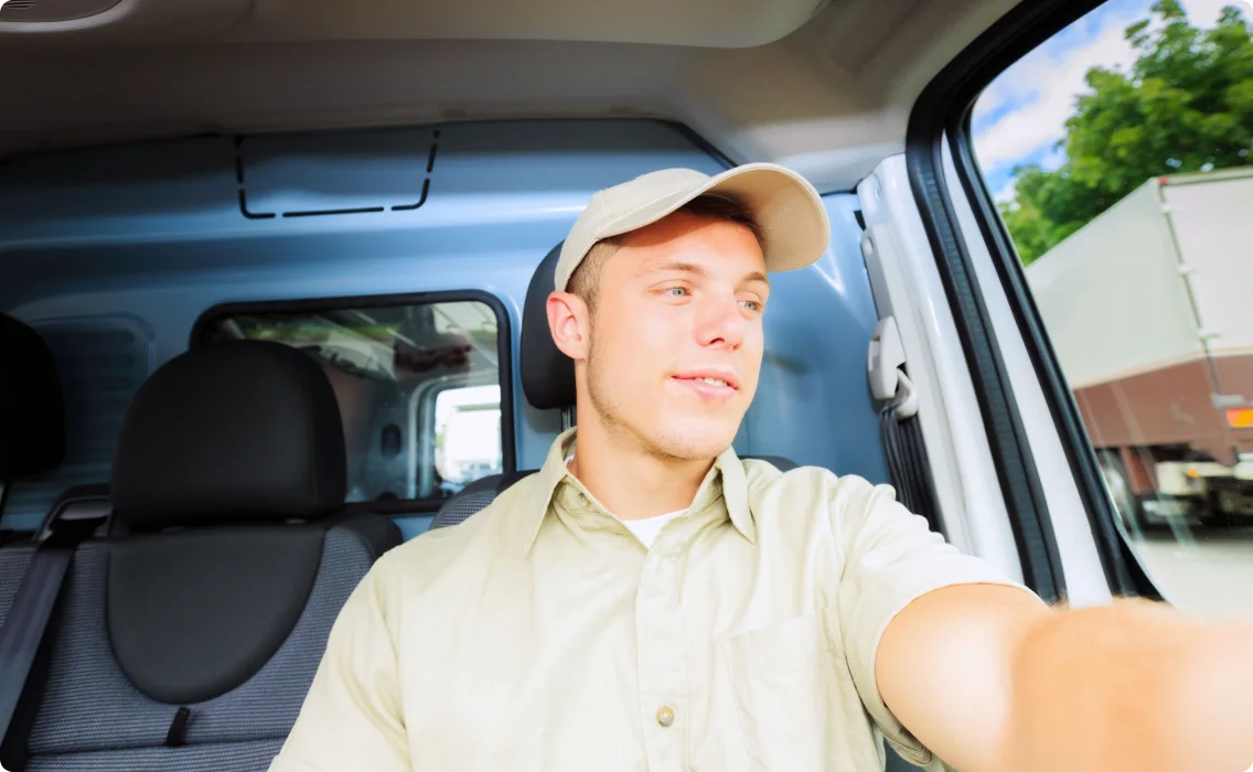 A man sitting in the driving seat looking out side the vehicle