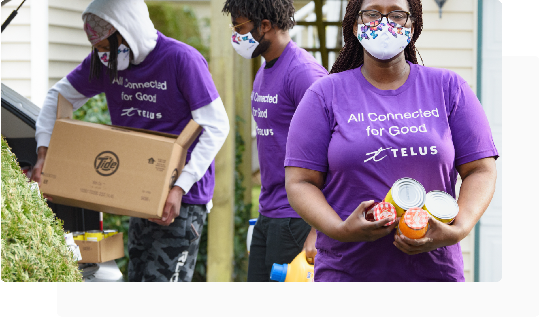 Three TELUS team members help distribute food items, symbolizing our commitment to give back to communities. 