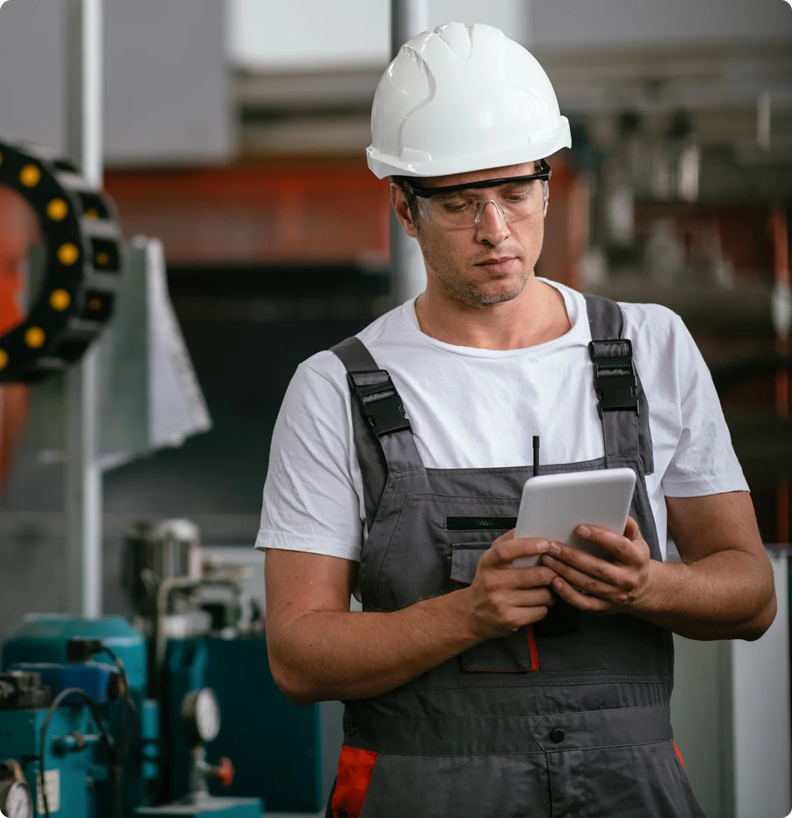 Manufacturing technician using tablets for equipment monitoring in industrial facilities.