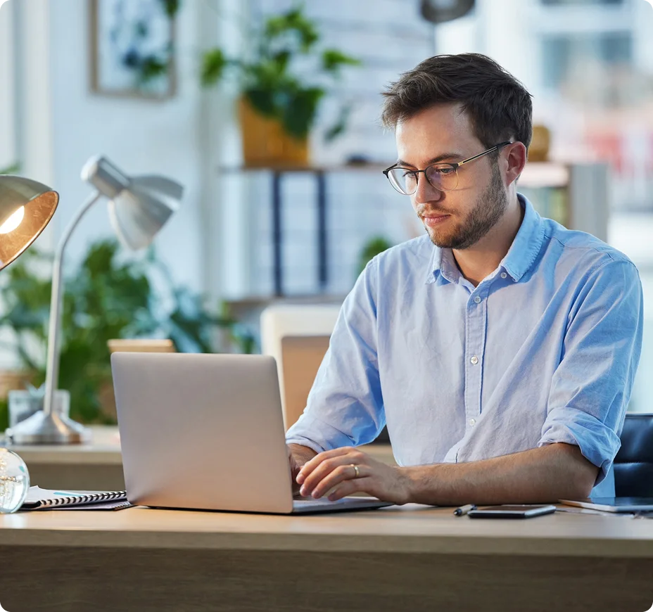 Professional working on laptop at desk in bright home office.