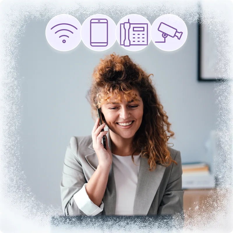 Business owner on a laptop; purple icons for Wi-Fi, mobile, phone and security camera, promoting bundles.
