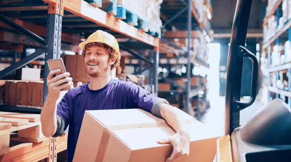 Person using a mobile device while working in a warehouse.