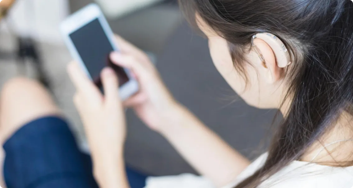 Une femme avec un appareil auditif utilise un téléphone intelligent