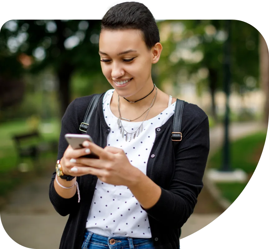 A young adult smiling as she connects with friends on a smartphone she received through the Mobility for Good program.