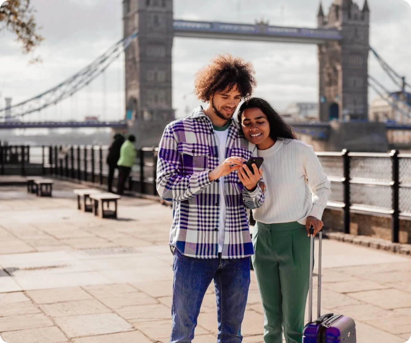 Couple using smartphone while traveling with luggage