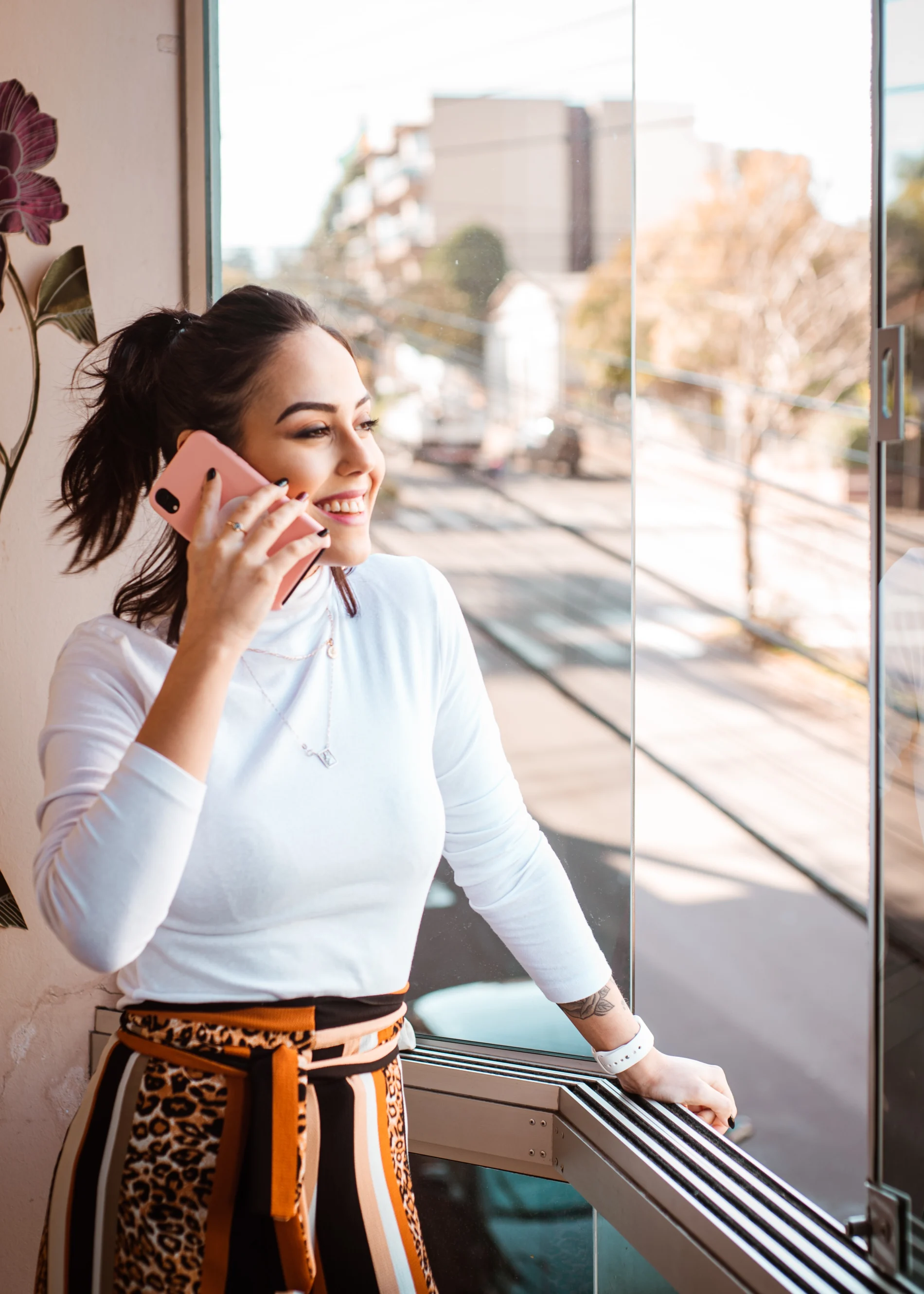 Women holding her phone looking outside the window in her office