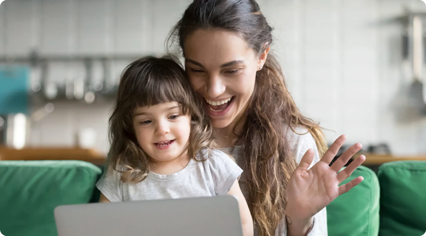 A woman and young child smiling while viewing a laptop