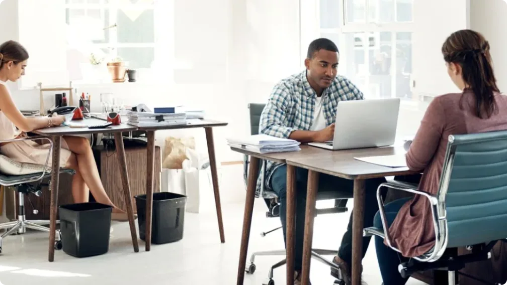 A man and two women working at their desks.