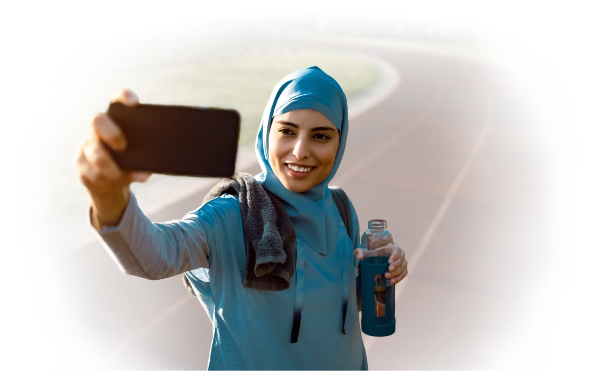 Une femme se prend en photo sur une piste de course, symbolisant la vitesse du réseau 5G de TELUS.