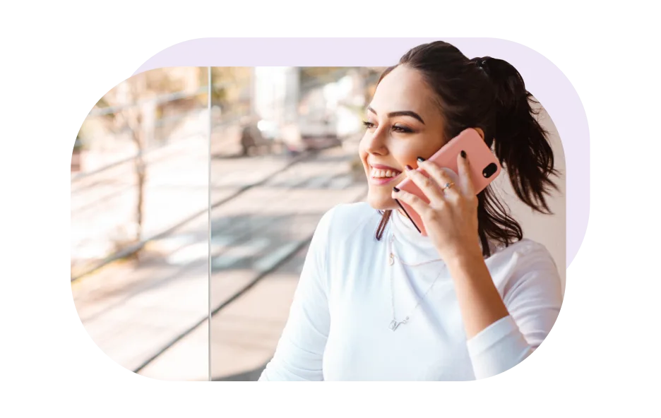 A woman is smiling while talking on the phone. 