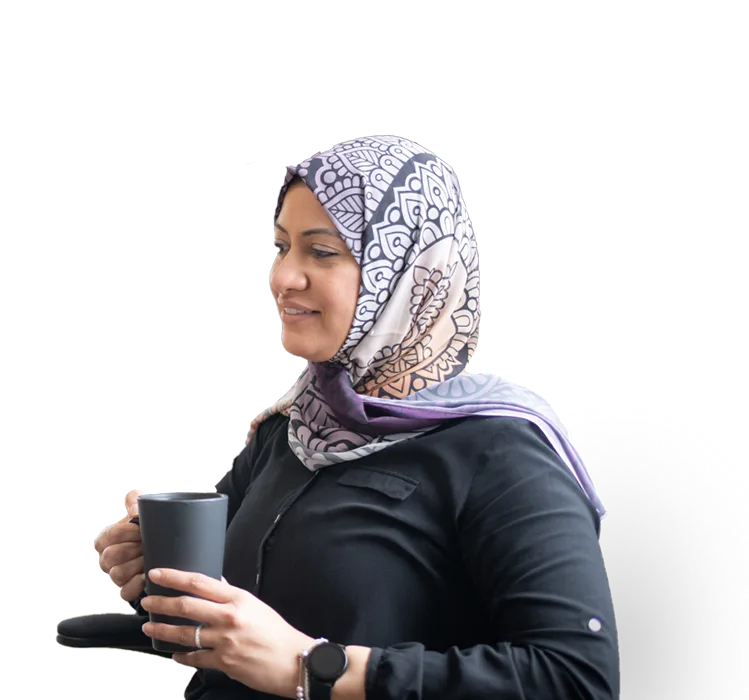 Une femme portant un hijab tient sa tasse de café