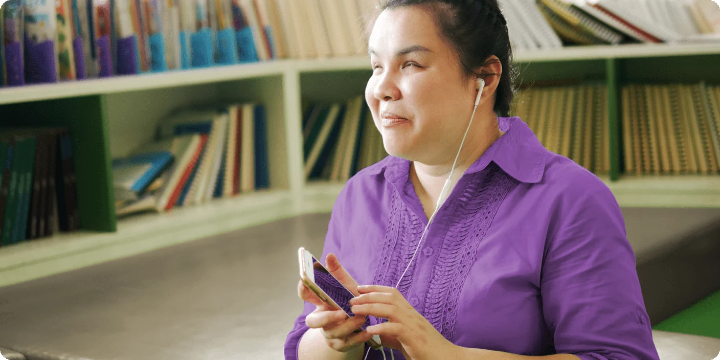 A person wearing headphones plugged into a smartphone