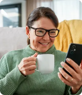 Older woman smiling while using the TELUS Health MyCare mobile app on her smartphone.