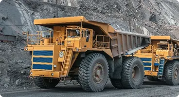 Large mining haul trucks transporting materials at mining operation.