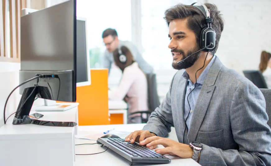 Person wearing a headset while sitting in an office in front of their desktop computer.