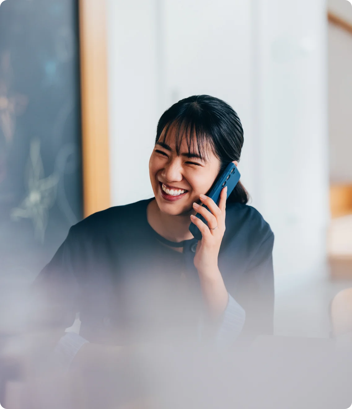 Smiling professional on a smartphone call in an office.