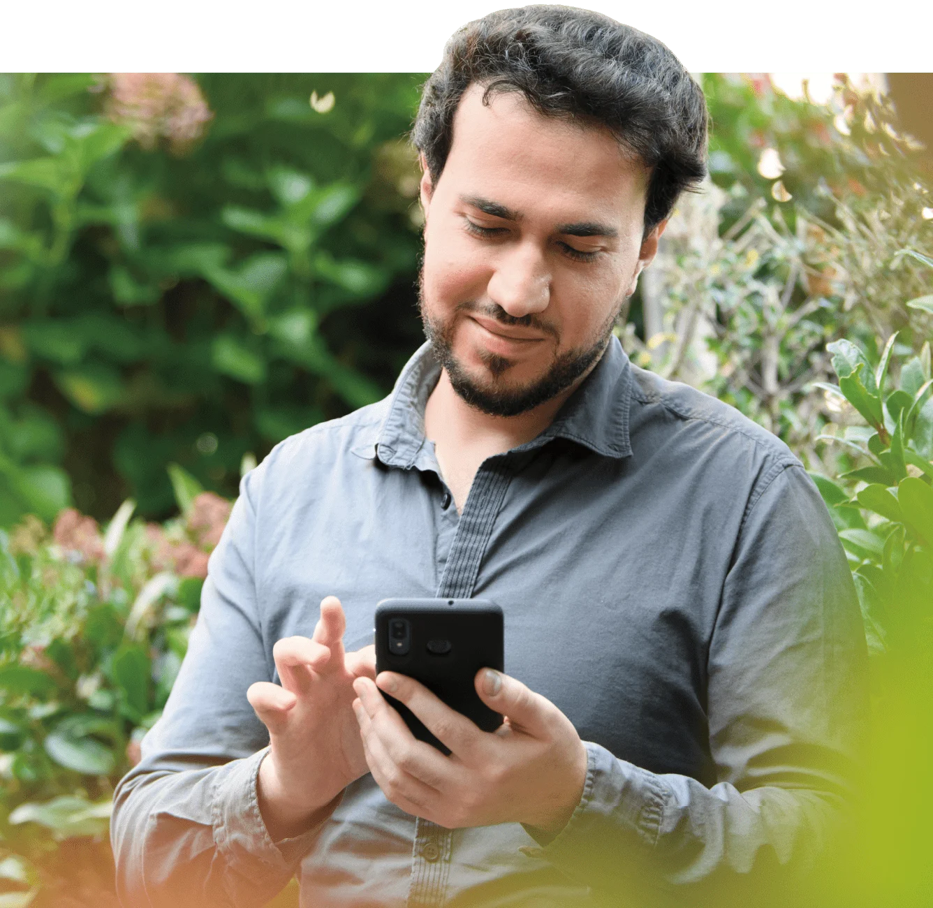 A man in a garden viewing a smartphone