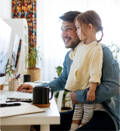 Un père et sa fille assis à un bureau regardent un écran d’ordinateur