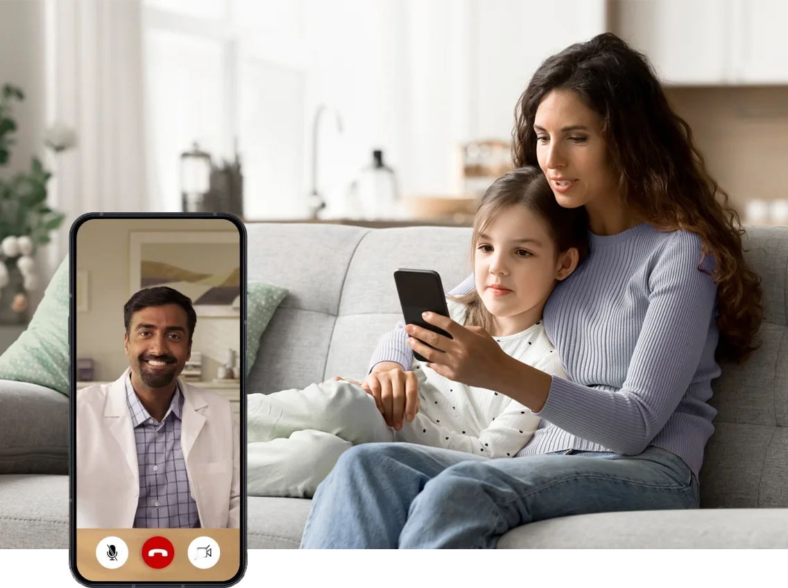 une femme assise par terre jouant avec son enfant et utilisant son téléphone portable pour accéder à des soins de santé virtuels