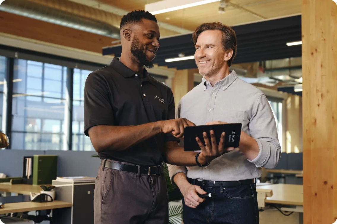 TELUS Business representative pointing to a tablet for a smiling business owner