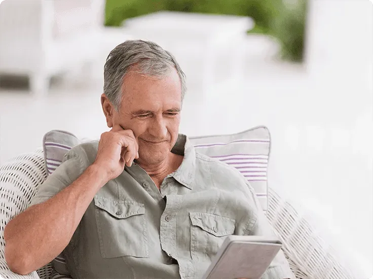 A man sitting in a chair enjoying high-speed internet on his tablet.