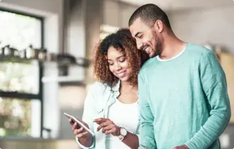 A couple stands together, looking at a smartphone