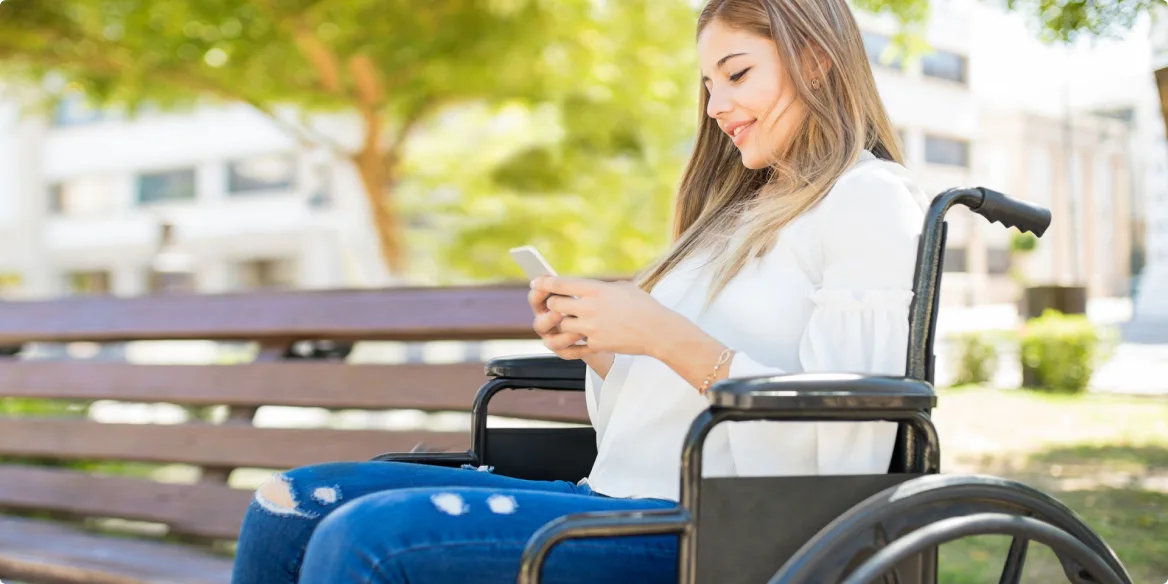 A woman in a wheelchair reading her smartphone