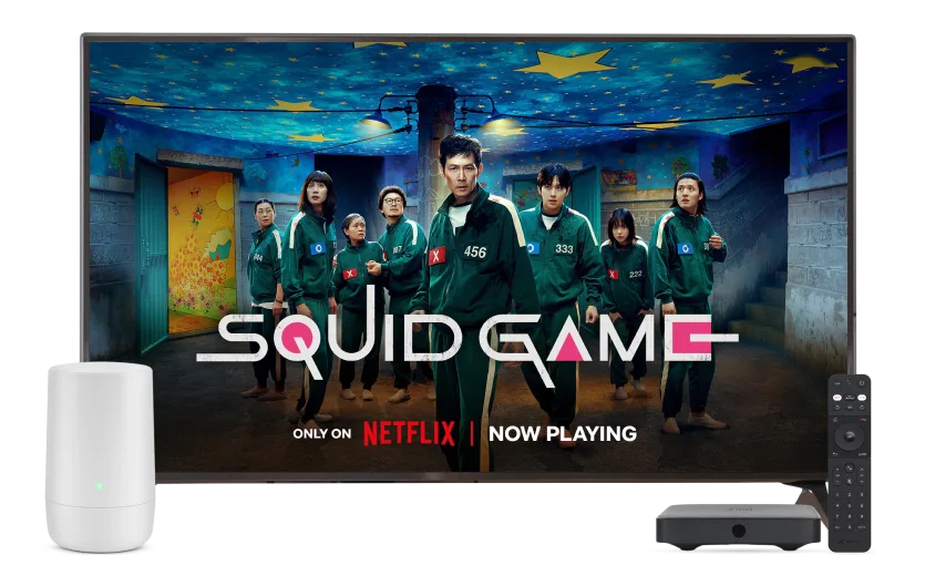 A TV screen displays Nextflix’s Squid Game S3 series. A wifi router is on the left bottom corner of the TV. A TELUS TV Digital Box and a TELUS Bluetooth remote are in the bottom right corner.