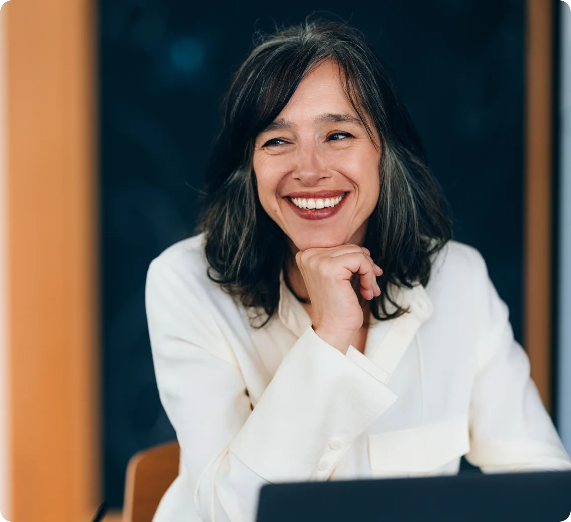 Smiling professional at a desk, laptop in the foreground.