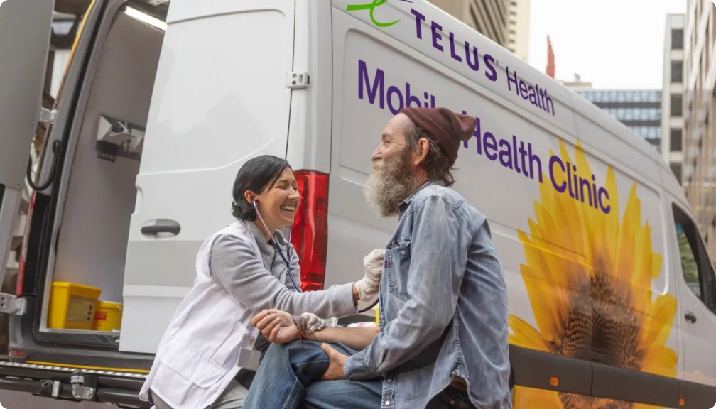 a man and a woman sitting next to a TELUS Mobile Health Clinic