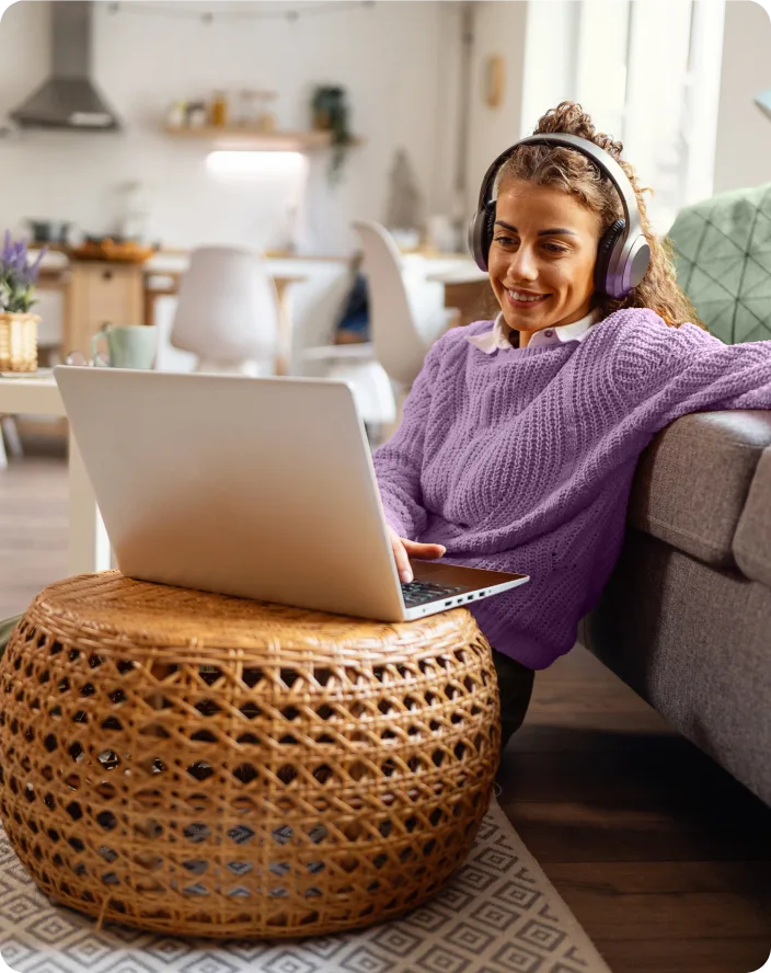 Image d’une jeune femme assise sur le sol de son salon, lisant le blogue Énergie intelligente de TELUS sur son ordinateur portable. Elle est habillée de manière décontractée et son expression faciale est calme et détendue.