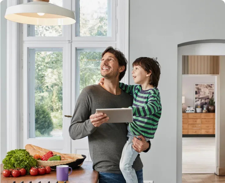 Father and child in modern kitchen using tablet for home automation