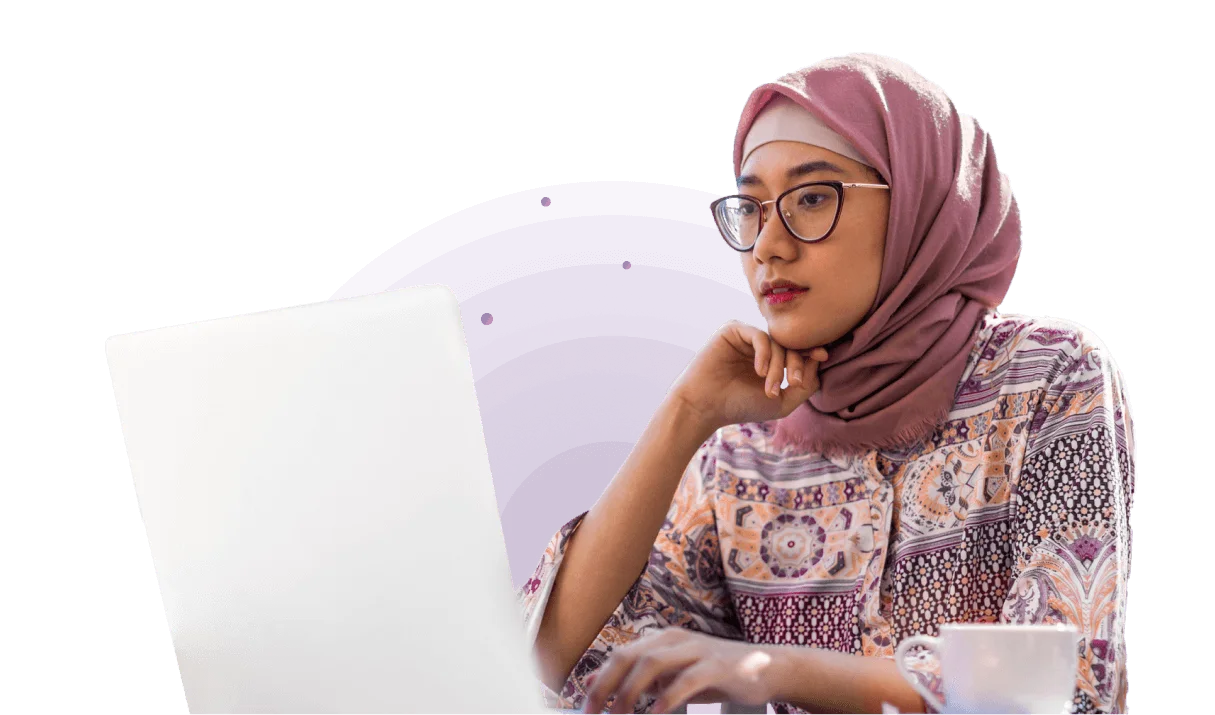 A woman in a hijab looks at a computer monitor.