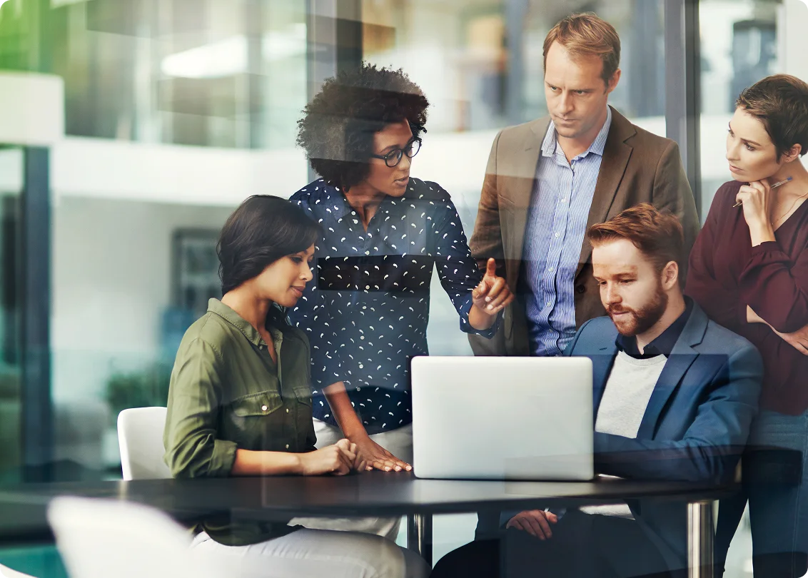 Business team collaborating around laptop in modern office meeting.
