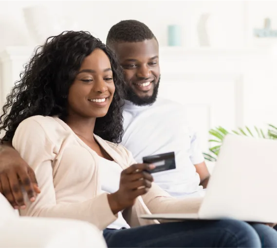 A seated couple paying their bill online using a laptop