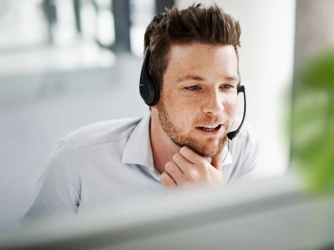 A person talking on the phone while looking down at a screen with a headset.
