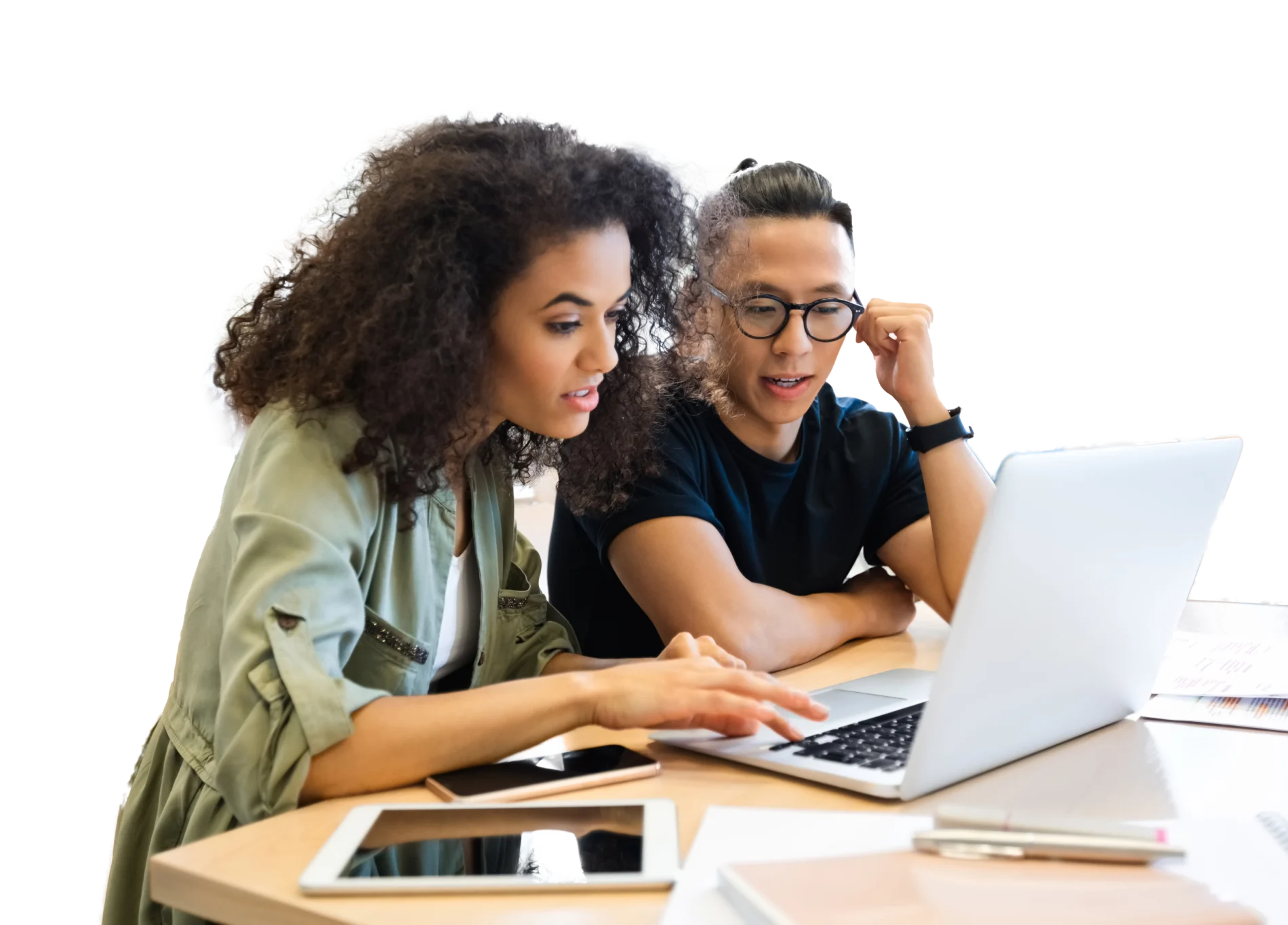 Two people seated at a table viewing a laptop with a tablet lying beside it