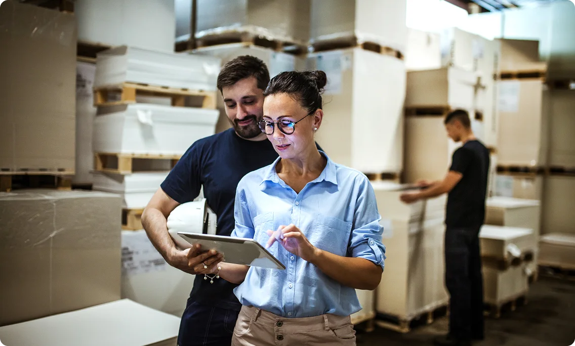Warehouse workers reviewing operations data on a tablet in a distribution facility.