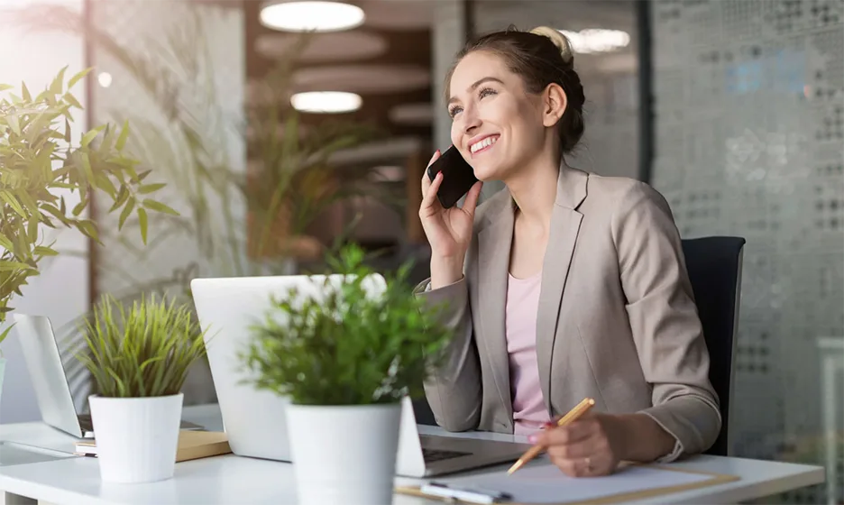 Une femme souriante au téléphone travaillant à son bureau