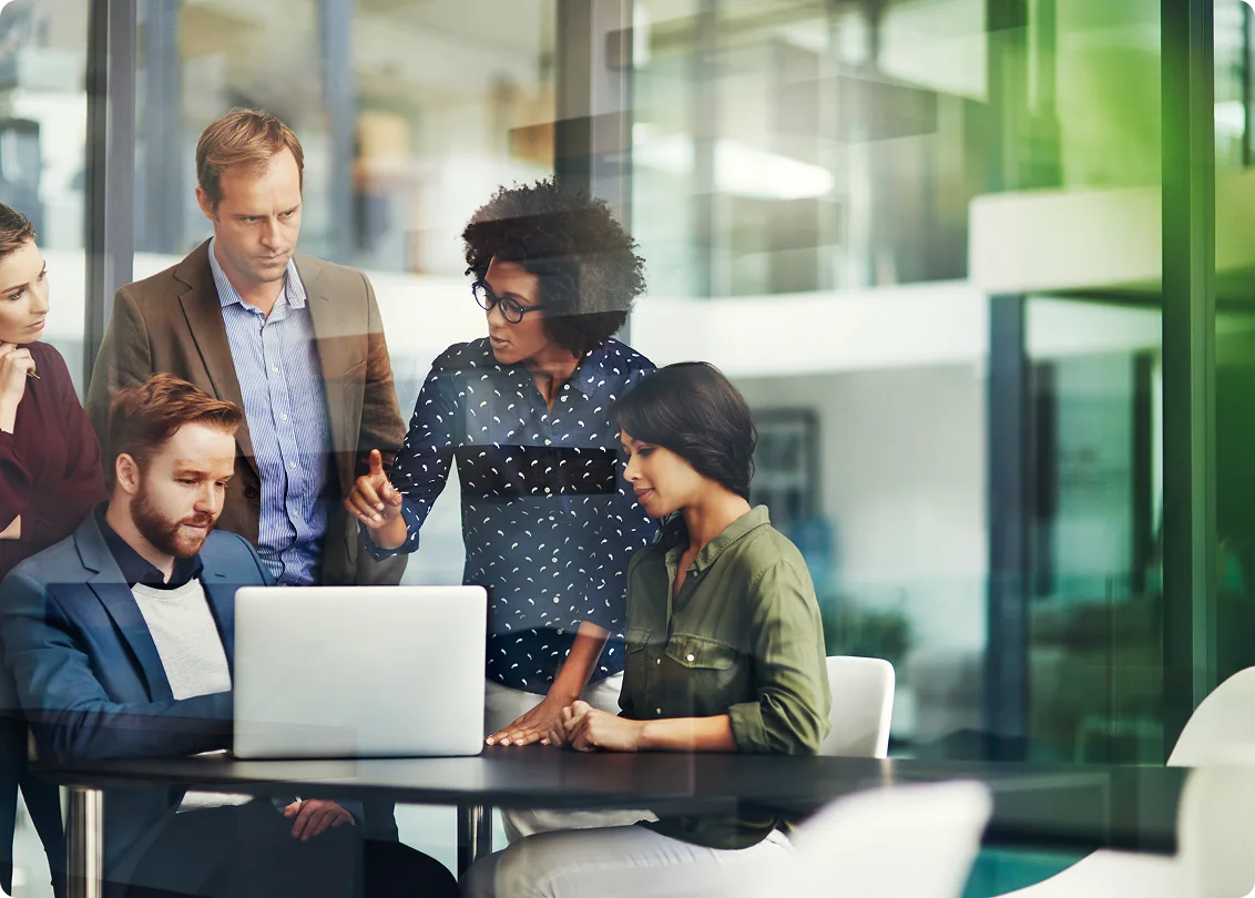 Business team collaborating around laptop in modern office meeting.