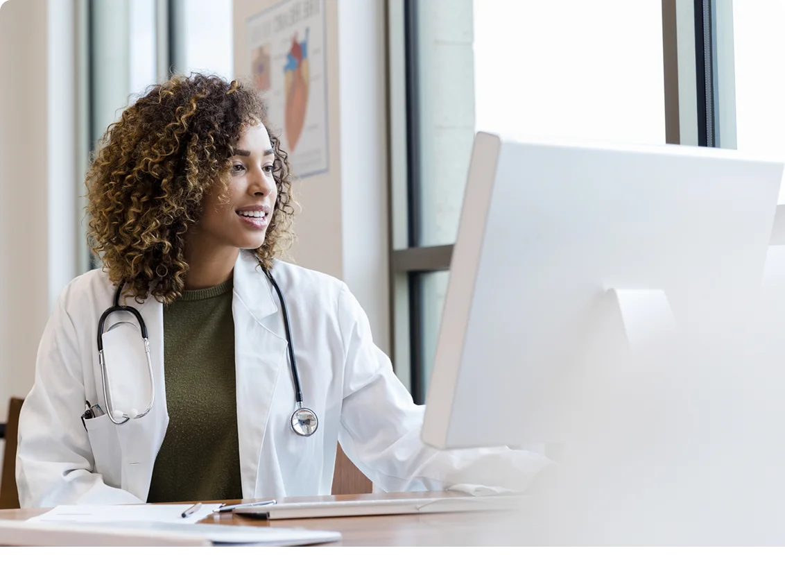 Healthcare professional working at a computer in a medical office.