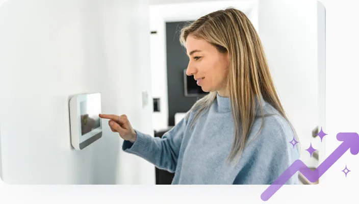 Femme réglant un thermostat intelligent tout en participant à un défi d’économie d’énergie pour obtenir des Récompenses TELUS. 