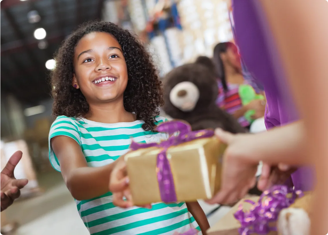 Young child hands out gifts at holiday toy drive